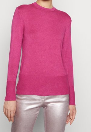 Fuchsia long-sleeve sweater in soft knit fabric with ribbed neckline and hem. Paired with shiny metallic silver pants.