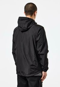 Black lightweight jacket made of textured fabric, featuring a hood, elastic cuffs, and a relaxed fit. No visible logos or patterns.