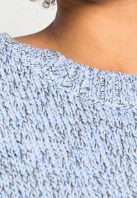Light blue knitted sweater featuring a ribbed neckline, textured weave, and subtle contrasting threads.
