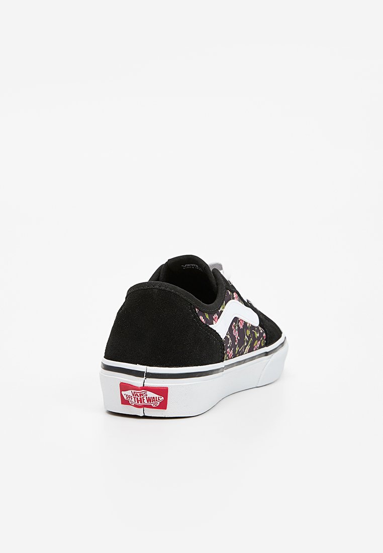 Sneakers en suède noir avec un imprimé floral sur le côté, des accents blancs et un logo Vans rouge à l'arrière. Design basse avec semelle en caoutchouc.