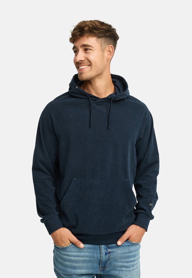 Marineblå hættetrøje lavet af tekstureret stof med en frontlomme, snorehætte og ribbede manchetter. Stylet med casual jeans.