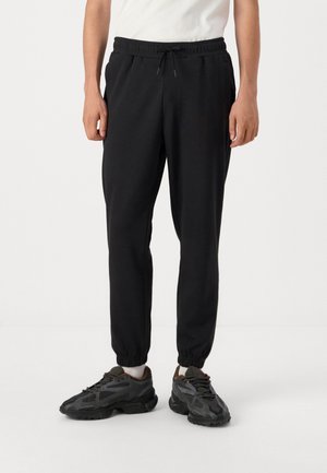 Zwarte joggingbroek met een elastische tailleband en verstelbare trekkoord, met taps toelopende pijpen en zijzakken. Makkelijk katoenmix stof.