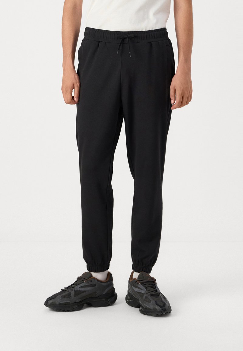 Sorte sweatpants med elastisk talje og justerbar snøre, der har tapered ben og sidelommer. Glat bomuldsblandingsstof.