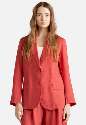 Červený lněný blazer s výstřihem do V, dvěma knoflíky a dvěma předními kapsami; lehká textura a mírně volný střih.