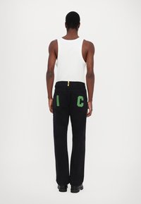 Black denim pants with green embroidered letters "I" and "C" on the back pockets. The jeans have a straight fit and feature a yellow tab on the waistband.