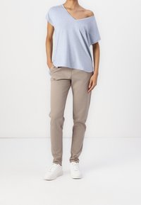 Ljusblå off-shoulder T-shirt med lös passform, kombinerad med beige slim-fit byxor och vita sneakers, med sidofickor.