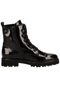 Bottine en cuir noir brillant avec semelle épaisse à crampons, fermeture éclair latérale et laçage avant avec œillets métalliques.