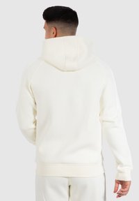 Witte hoodie met ribgebreide boorden en zoom, met een soepele textuur. De achterkant toont een eenvoudig ontwerp zonder opvallende patronen.