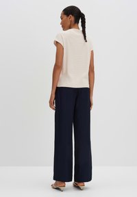 Cream knit top with short sleeves, textured design, paired with navy wide-leg trousers. Low-heel shoes visible. Simple and clean appearance.