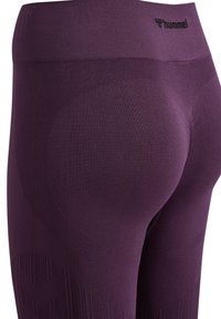 Lila aktiva leggings med en texturerad yta, konturerande design och en hög midja med varumärkeslogotypen på framsidan.