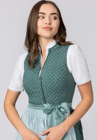 Dark green dirndl with white polka dots, featuring a fitted bodice, white puff sleeves, and a light blue skirt with a matching satin bow.