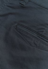 Material de culoare gri închis cu o textură subtilă în dungi, având un design al buzunarelor diagonale cu detalii de cusătură în contrast.