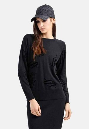 Maglione nero lavorato a maglia con collo rotondo e maniche lunghe, caratterizzato da un leggero motivo testurizzato. Abbinato a un berretto nero coordinato.