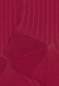 Gerippte Socken in einem tiefen Rosaton, mit einer glatten Textur und verstärktem Zehenbereich. Ein subtiler Glanz verleiht dem Stoff Tiefe.