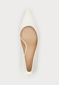 Fehér, hegyes orrú cipő sima bőrből, oldalán kivágott mintázattal és gyémánt díszítéssel a sarkán.