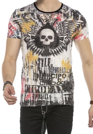 Camiseta de manga corta con un gráfico de calavera en forma de pica, en blanco y negro con salpicaduras multicolor y texto. La tela parece tener textura.