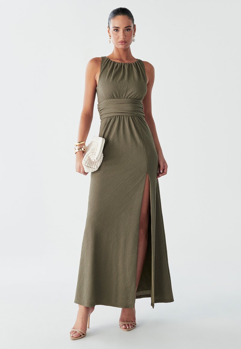 Vestido largo verde oliva con corpiño ajustado, cuello fruncido y abertura lateral. Presenta tela texturizada y un diseño suave y fluido.