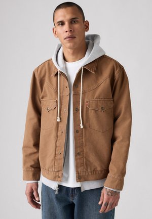 Brown denim jacket with button-up front, two chest pockets, and a gray hooded sweatshirt underneath. Features a casual fit and textured fabric.