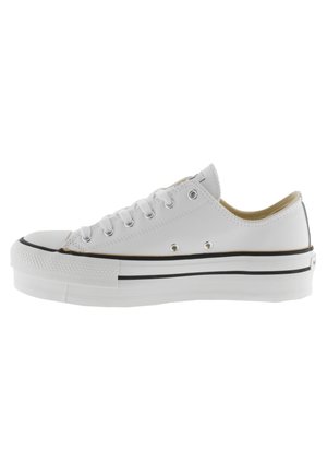 Sneaker bassa in tela bianca con suola in gomma nera, punta arrotondata, occhielli in metallo e striscia nera a contrasto attorno alla suola.