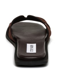 Bruine suède slidesandalen met een platte zwarte zool, met een minimalistisch ontwerp en een gelabelde binnenzool. Geen onderscheidende patronen of accenten.