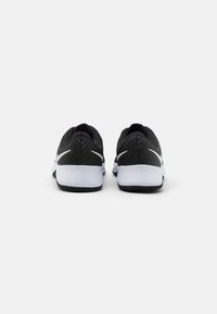 Para czarno-białych trampek Nike pokazana od tyłu z widocznymi białymi logotypami swoosh na obcasach, na jednolitym białym tle.