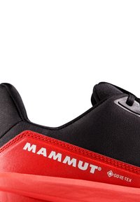 Scarpa da trekking nera e rossa con tomaia in materiale sintetico testurizzato, logo in evidenza e branding GORE-TEX, profilo elegante e lacci.