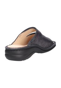 Black leather slip-on sandal with a curved design, soft interior, and textured surface. Features a low, solid black rubber sole.