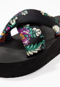 Černé sandály s pevnou polstrovanou podrážkou a polstrovanými tkaninovými popruhy vyšívanými barevnými květinovými vzory.