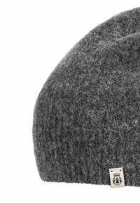 Dark gray woolen knit beanie with a small white fabric tag featuring a black emblem and text on the lower edge.