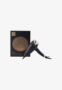 Sèche-cheveux professionnel noir avec un accent argenté. Comprend une boîte rectangulaire noire avec un motif circulaire doré et un marquage.