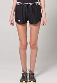 Czarne sportowe szorty z białym paskiem z logo, zakończone ściągaczem i z nogawkami sięgającymi powyżej kolan. Do tego czarne buty do biegania.