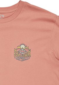 T-shirt en coton rose clair avec un design graphique coloré représentant des montagnes, un soleil et le texte "Billabong Australia" sur la poitrine.