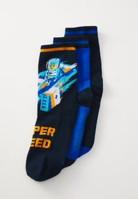 Drei Paar Socken: ein navyfarbenes Paar mit einem Grafikdesign einer Rennstrecke und einer Figur, orangefarbener Schriftzug "SUPER SPEED", sowie zwei einfarbige blaue Socken.