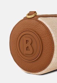 Round bag with a textured tan leather base, woven beige accents, and a circular logo. Features a gold zipper and leather pull tab.