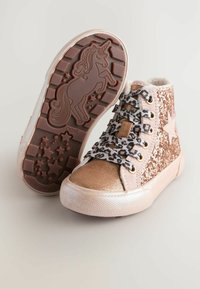 Baskets montantes roses et dorées avec des paillettes, des lacets à imprimé léopard, un accent en forme d'étoile, et un motif de licorne sur la semelle en caoutchouc texturée.