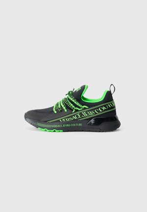 Schwarzer Sportschuh mit grünen Akzenten, ausgestattet mit einem Mesh-Obermaterial, dekorativen Schnürsenkeln und dem Branding "Versace Jeans Couture" an der Seite.