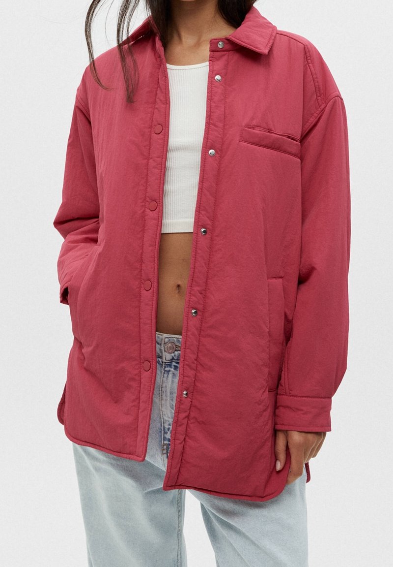 Veste matelassée rouge avec fermeture à boutons, poche poitrine et poches latérales. Fabriquée en tissu léger avec une coupe décontractée.