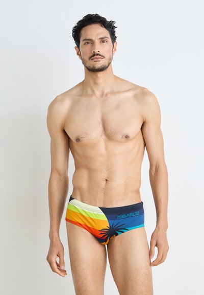 Caleçons de bain à rayures multicolores, mettant en avant des nuances d'orange, de jaune, de vert et de bleu avec un motif de palmier et un accent de logo.