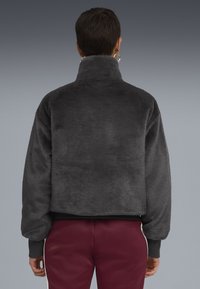 Gray fleece jacket with a high collar and cropped design. Features ribbed cuffs and hem, soft texture, and a smooth finish.