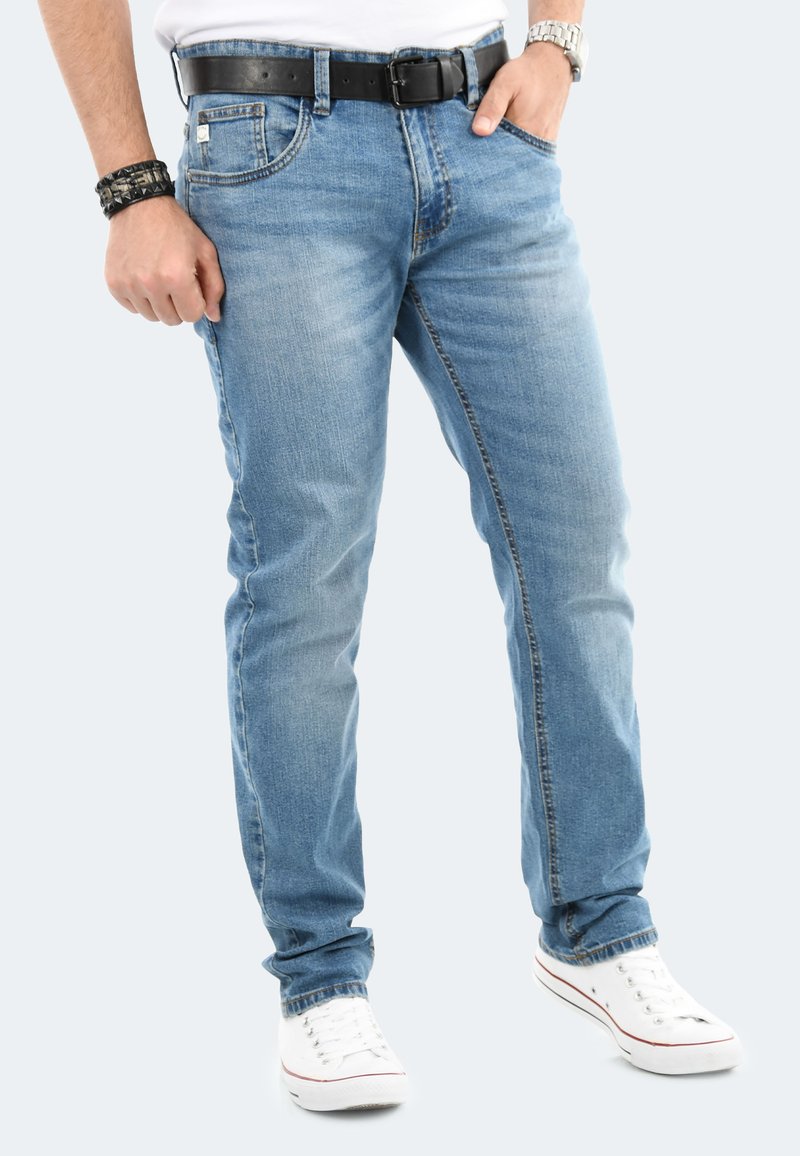 Helle Jeans aus Denim im Straight-Leg-Design, mit dezentem Verblassen und fünf Taschen. Kombiniert mit einem schwarzen Gürtel und weißen Schuhen.