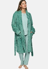 Teal, gestructureerde fleece badjas met een zigzagpatroon, lange mouwen en twee voorzakken, gedragen over een bijpassende lichtteal top en broek.