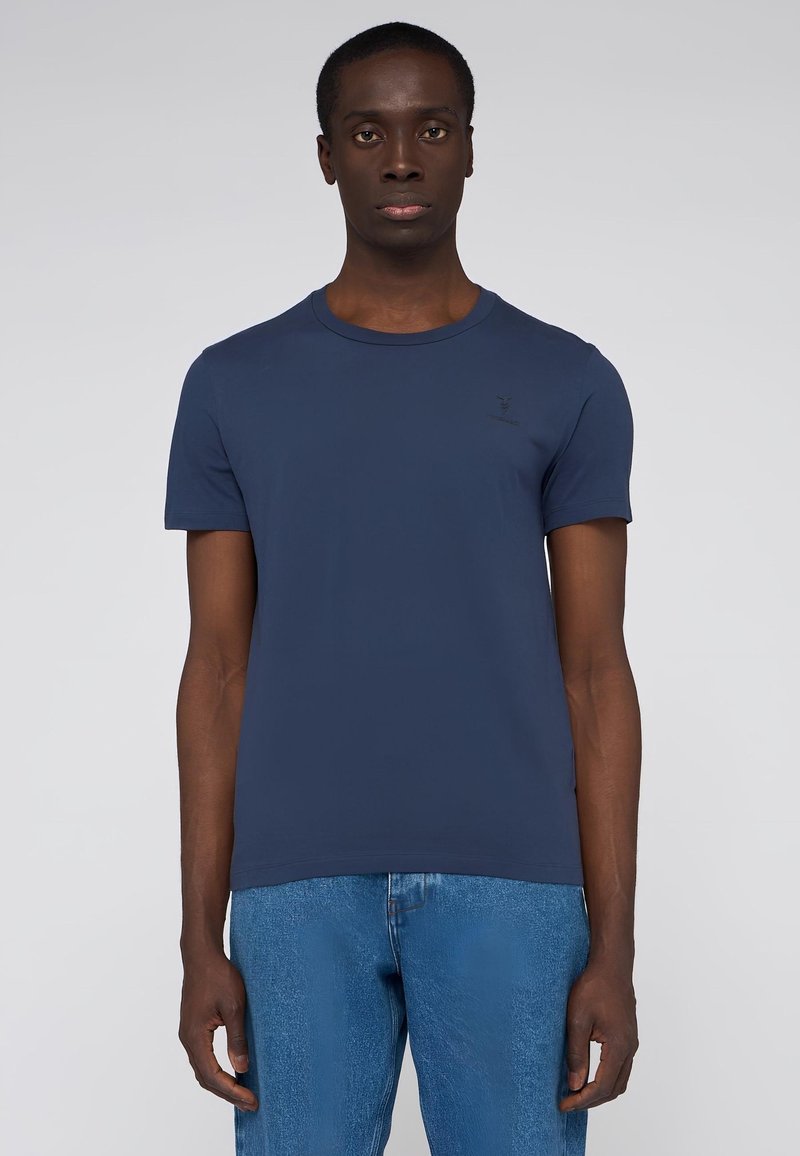 Námořnická modrá tričko s krátkým rukávem vyrobené z měkké bavlny, se klasickým krkem a malým logem na hrudi.