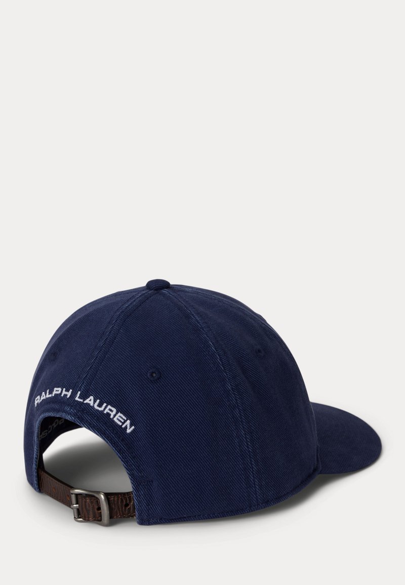 Gorra de béisbol azul marino con correa ajustable de cuero marrón, hebilla metálica y texto blanco "RALPH LAUREN" bordado encima de la abertura.
