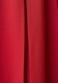 Tessuto rosso con una texture liscia, caratterizzato da un dettaglio plissettato. Il materiale sembra essere leggero e presenta un colore uniforme in tutto il capo.