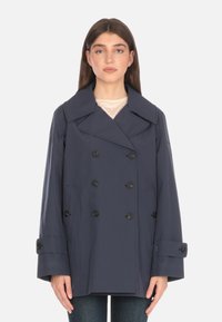 Cappotto doppiopetto blu navy con grandi rever, bottoni neri e tasche laterali. Presenta una vestibilità rilassata e una texture liscia.