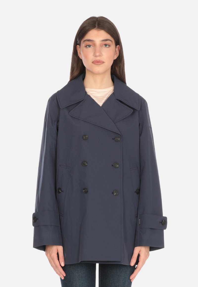 Cappotto doppiopetto blu navy con grandi rever, bottoni neri e tasche laterali. Presenta una vestibilità rilassata e una texture liscia.