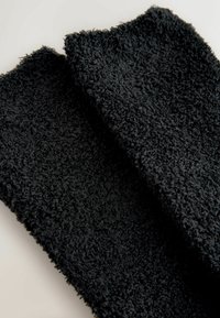 Black textured towels with a fluffy, soft surface. Each towel features a slightly uneven edge, enhancing the tactile quality.
