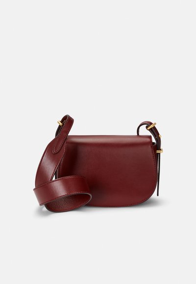 Bolsa de ombro em pele bordô com forma arredondada, alça ajustável e detalhes em metal dourado. Textura suave com design minimalista.