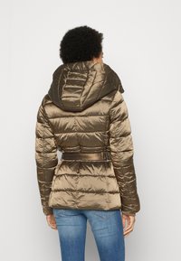 Giubbotto imbottito in verde oliva metallico, con un grande cappuccio, vita con cintura, texture trapuntata e maniche lunghe.