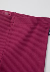 Burgundy ribattu kangas, jossa on nappikiinnitys vyötäröllä. Ominaisuuksiin kuuluu puhdas, saumatön muotoilu ilman näkyviä kuvioita tai metalliosia.